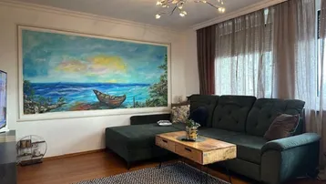 Gemütliches Wohnzimmer mit großem Wandgemälde, bequemer Couch und Holzboden.
