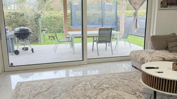 Heller Wohnbereich mit großzügigem Zugang zur Terrasse und Blick auf den Garten mit Trampolin.