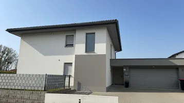 Modernes Einfamilienhaus mit weißer Fassade, grauen Akzenten und integrierter Garage.