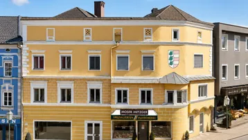 Historisches Gebäude mit gelber Fassade und traditioneller Architektur in einer städtischen Umgebung.
