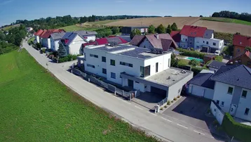 Luftaufnahme des modernen Hauses mit Photovoltaikanlage und der ländlichen Umgebung.