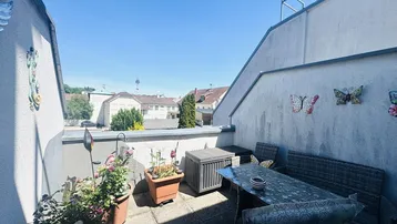 Sonnige Dachterrasse mit Gartenmöbeln und Blick auf die umliegenden Häuser.