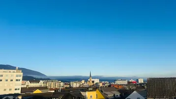 Panoramablick über die Stadt mit Bergen im Hintergrund und blauem Himmel am Morgen.