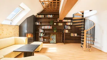Gemütliches Dachgeschoss-Wohnzimmer mit Kamin, eingebauten Bücherregalen und Dachfenstern.