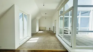 Helles Dachgeschosszimmer mit Teppichboden, großen Fenstern und Zugang zu einer Terrasse.