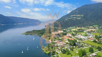 Panoramablick auf den Ossiacher See mit umliegenden Bergen und Siedlungen.