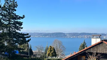 Panoramablick auf den See und die umliegende Landschaft an einem sonnigen Tag.