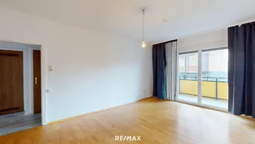 Helles Wohnzimmer mit Parkettboden und Zugang zu einem Balkon, ideal für entspannte Stunden.