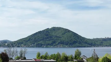 Panoramablick auf den See und die umliegenden Berge mit einem Supermarkt im Vordergrund.