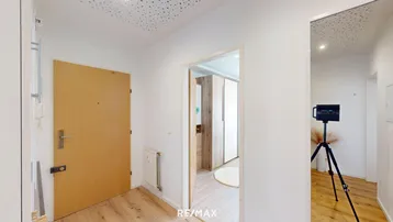 Heller Eingangsbereich mit Holzboden und Zugang zu weiteren Räumen der Wohnung.