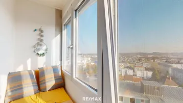 Helle Loggia mit gemütlicher Sitzbank und weitem Blick über die Stadt.
