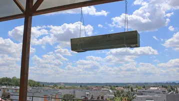 Überdachte Terrasse mit weitem Blick über die Stadt und blauen Himmel, ideal zum Entspannen.