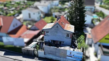 Luftaufnahme eines Hauses mit rotem Ziegeldach und umliegender Bebauung in einem Wohngebiet.
