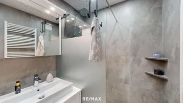 Modernes Badezimmer mit großformatigen Fliesen, Duschbereich und beheiztem Handtuchhalter.