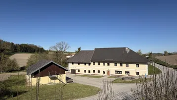 Großes ländliches Anwesen mit mehreren Gebäuden und weitem Blick in die Natur.