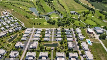 Luftaufnahme einer modernen Wohnanlage mit Einfamilienhäusern und angrenzendem Golfplatz.