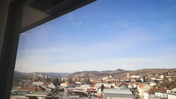 Weitblick über eine Stadt mit Hügeln im Hintergrund an einem sonnigen Tag.