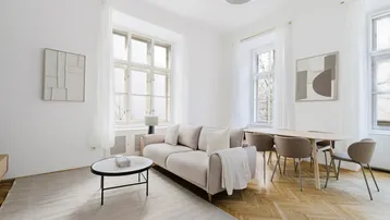 Helles Wohn- und Esszimmer mit Fischgrätparkett, beigem Sofa und modernem Esstisch.