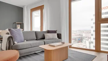 Helles Wohnzimmer mit modernem Sofa, Holztisch und großen Fenstern mit Stadtblick.
