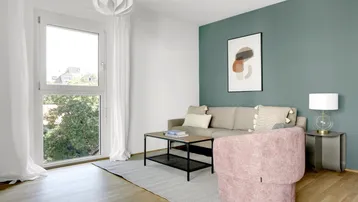 Helles Wohnzimmer mit modernem Sofa, Couchtisch und grüner Akzentwand.