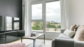 Helles Wohnzimmer mit modernem TV-Möbel, bequemer Couch und Blick auf die Stadt.
