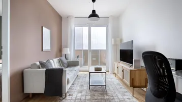 Helles Wohnzimmer mit modernem Sofa, TV-Möbel und Zugang zum Balkon.