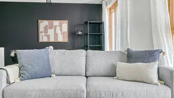 Gemütliches Wohnzimmer mit modernem Sofa, dunkler Akzentwand und stilvoller Dekoration.