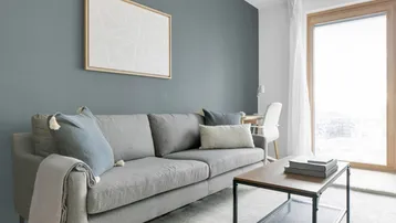 Helles Wohnzimmer mit modernem Sofa, stilvoller Wandkunst und Zugang zum Balkon.