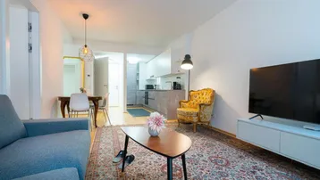 Gemütlicher offener Wohn- und Essbereich mit Teppichboden, Sofa und Blick zur modernen Küche.
