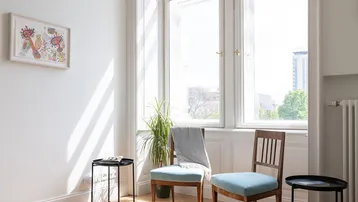 Helles Schlafzimmer mit Fischgrätparkett, hohen Fenstern und viel Tageslicht.