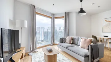 Helles Wohnzimmer mit großen Fenstern, Stadtblick und modernem Interieur.