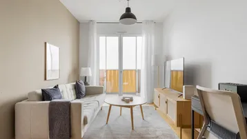 Helles Wohnzimmer mit modernem Sofa, Holzboden und Zugang zum Balkon.