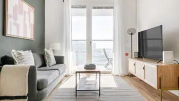 Helles Wohnzimmer mit modernem Sofa, Holzboden und Zugang zum Balkon.