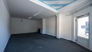 Geräumiger, leerer Innenraum mit Teppichboden und einer Decke mit blauen Akzenten, ideal für gewerbliche Nutzung.