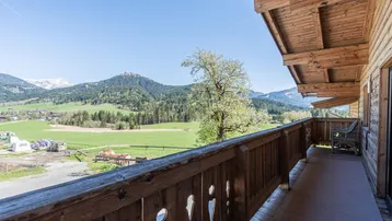 Geräumiger Holzbalkon mit traditionellem Geländer und weitem Blick auf die umliegende Berglandschaft.
