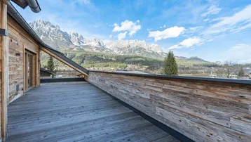 Geräumige Holzterrasse mit atemberaubendem Blick auf die umliegende Berglandschaft und den blauen Himmel.