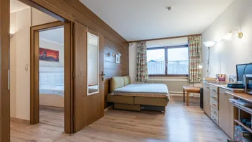 Gemütliches Schlafzimmer mit Holzwänden, Laminatboden und Blick auf die Umgebung.