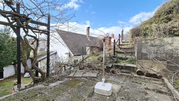 Obere Terrasse mit Blick auf die Dächer der Nachbarhäuser und eine bewachsene Pergola.