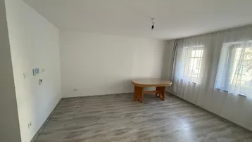 Helles Zimmer mit Laminatboden und einem kleinen Holztisch, bereit zur individuellen Gestaltung.