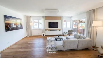 Modernes Wohnzimmer mit Holzboden, bequemer Couch und großem Fernseher.