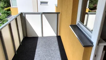 Sonniger Balkon mit Bergblick und Teppichboden, ideal für entspannte Stunden im Freien.