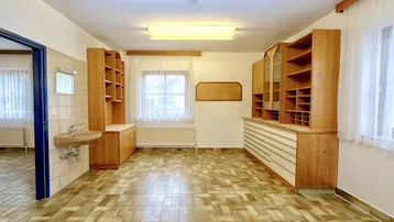 Geräumiger Büroraum mit Holzregalen, einem Waschbecken und Fliesenboden, ideal für gewerbliche Nutzung.