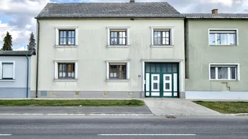Fassade eines Wohnhauses mit Garage und Fenstern, direkt an einer Straße gelegen.