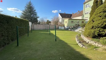Großer, gepflegter Gartenbereich mit Rasenfläche, Hecke und Wäscheleinen unter blauem Himmel.