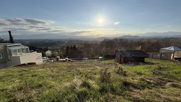 Weitläufiges Grundstück mit Panoramablick auf die umliegende Landschaft und Berge unter strahlendem Himmel.