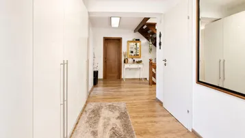 Heller Flur mit integrierten weißen Schränken, Holzfußboden und Zugang zur Treppe.