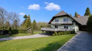 Freistehendes Haus mit großem Garten, Auffahrt und mehreren Balkonen in ländlicher Umgebung.