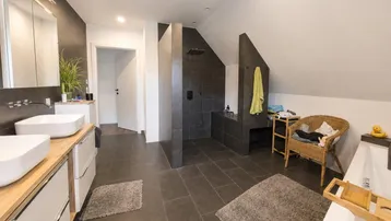 Modernes Badezimmer mit Doppelwaschbecken, großer begehbarer Dusche und Badewanne unter Dachschräge.