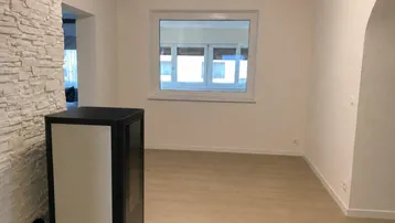 Helles Wohnzimmer mit modernem Kaminofen, Steinwand und hellem Holzboden.