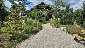 Ein charmantes Haus mit üppigem Garten und einem Kiesweg, der zum Eingang führt, unter einem bewölkten Himmel.